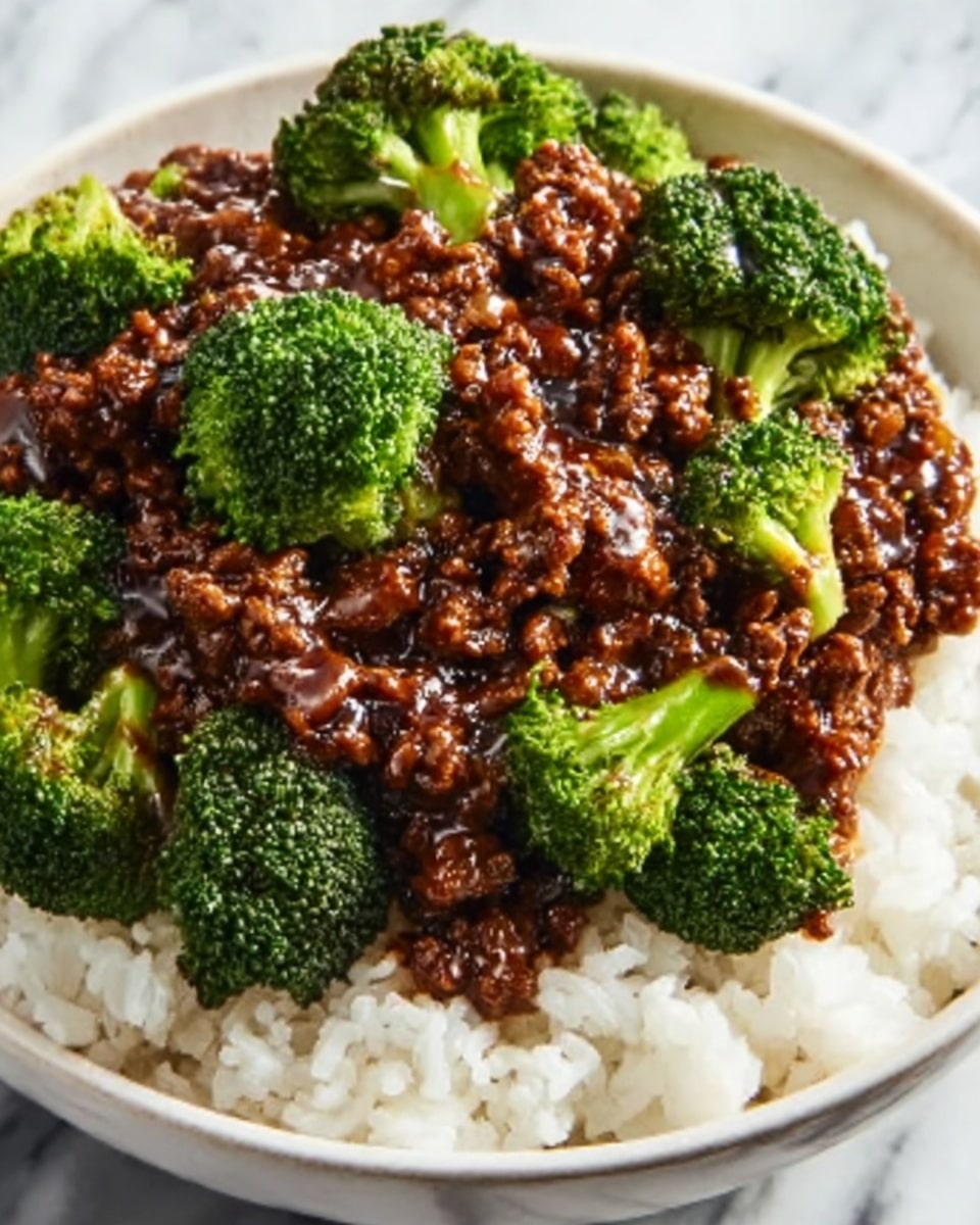 A close-up of a white bowl filled with three layers: the bottom layer is fluffy white rice, the middle layer consists of dark brown, saucy ground beef coated in a glossy sauce, and the top layer is made of bright green broccoli florets that are slightly steamed, adding a fresh texture. The bowl sits on a white marbled surface. photo taken with an iphone --ar 4:5 --v 7