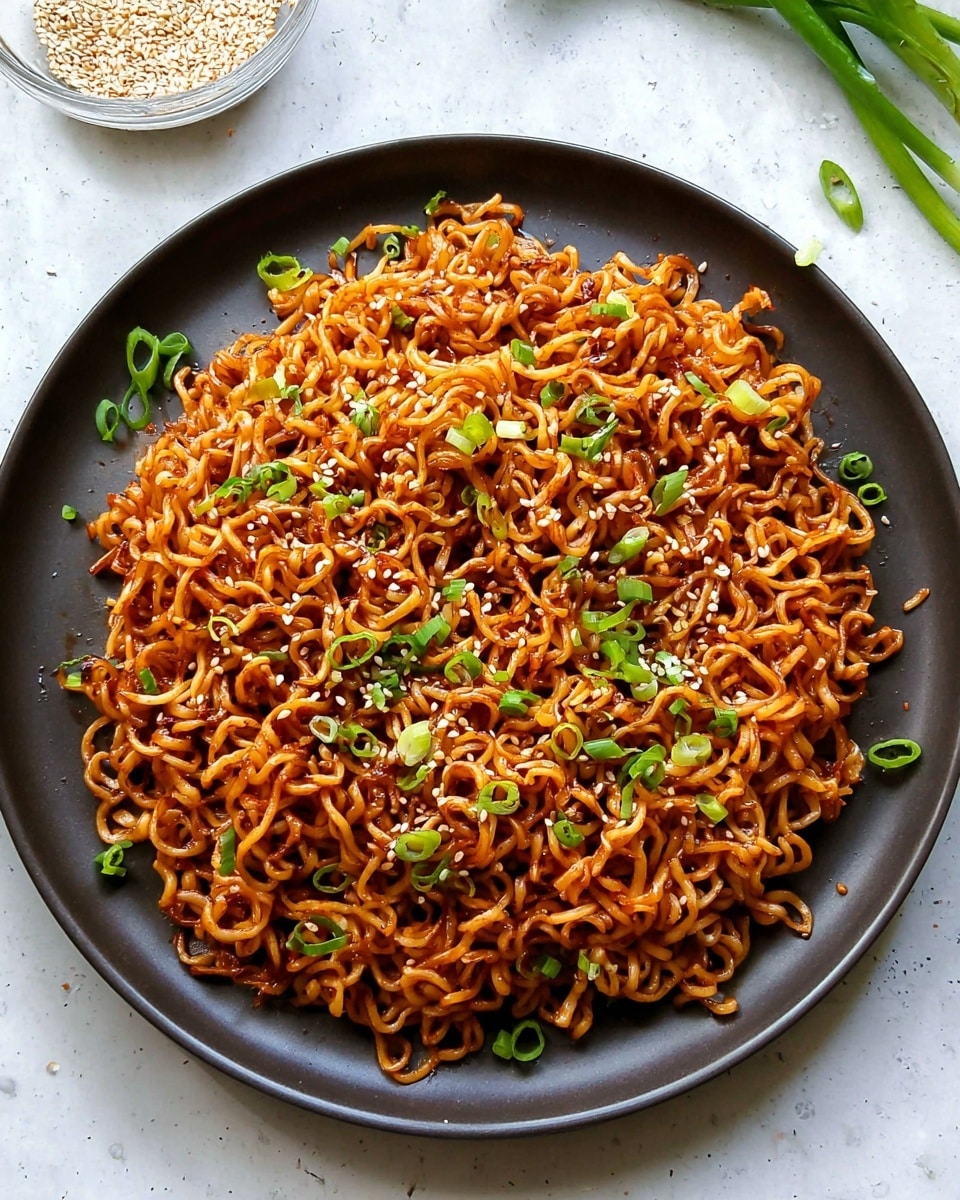 A large pile of cooked curly noodles with a reddish-brown sauce forms the single layer on a large white plate, scattered with bright green chopped spring onions and small white sesame seeds on top. The noodles have a shiny and slightly oily texture, with some darker caramelized spots, while the background is a white marbled surface with a small clear bowl of sesame seeds near the top left corner and a few green onion ends at the top right. Photo taken with an iphone --ar 4:5 --v 7