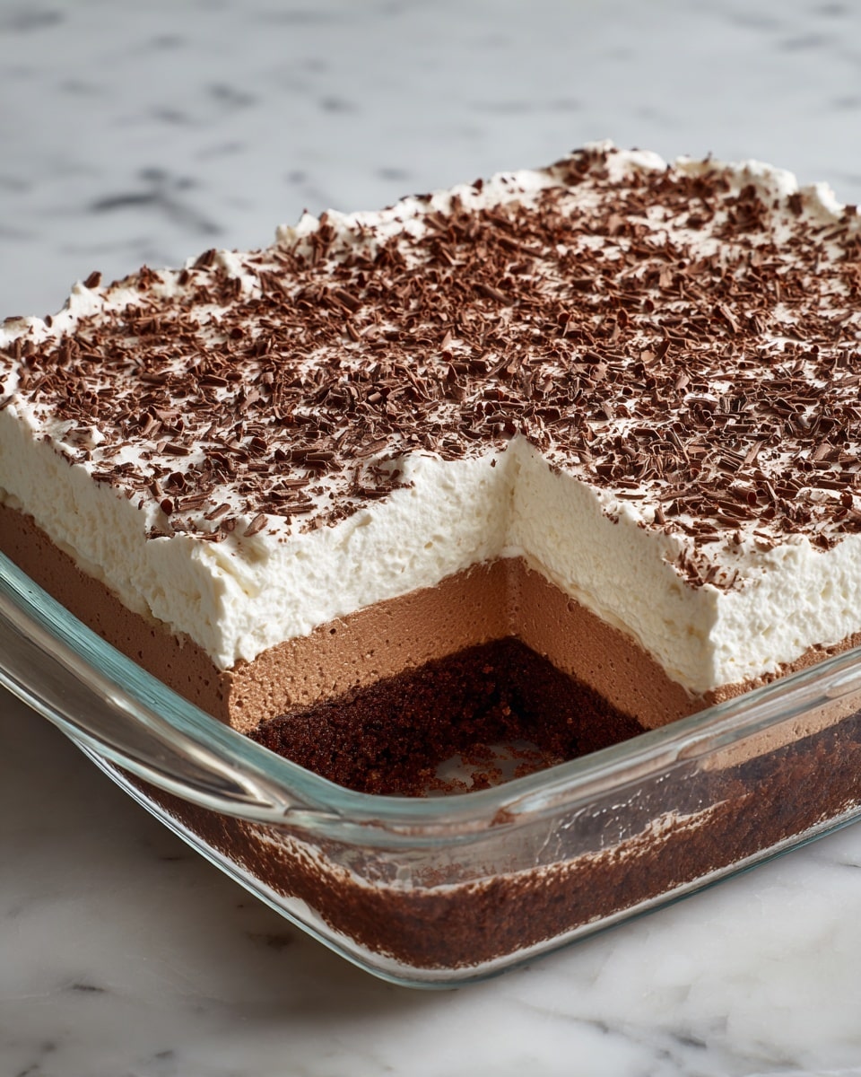 A three-layer dessert is shown in a rectangular glass dish placed on a white marbled textured surface. The bottom layer is a thick, dark brown, dense cake or brownie base with a slightly crumbly texture. Above it, there is a medium-thick middle layer of smooth, light brown chocolate mousse or pudding. The top layer is a thick, fluffy white whipped cream spread evenly, sprinkled generously with fine chocolate shavings. One large square piece is missing from the dish, revealing the cross-section of the layers clearly. photo taken with an iphone --ar 4:5 --v 7