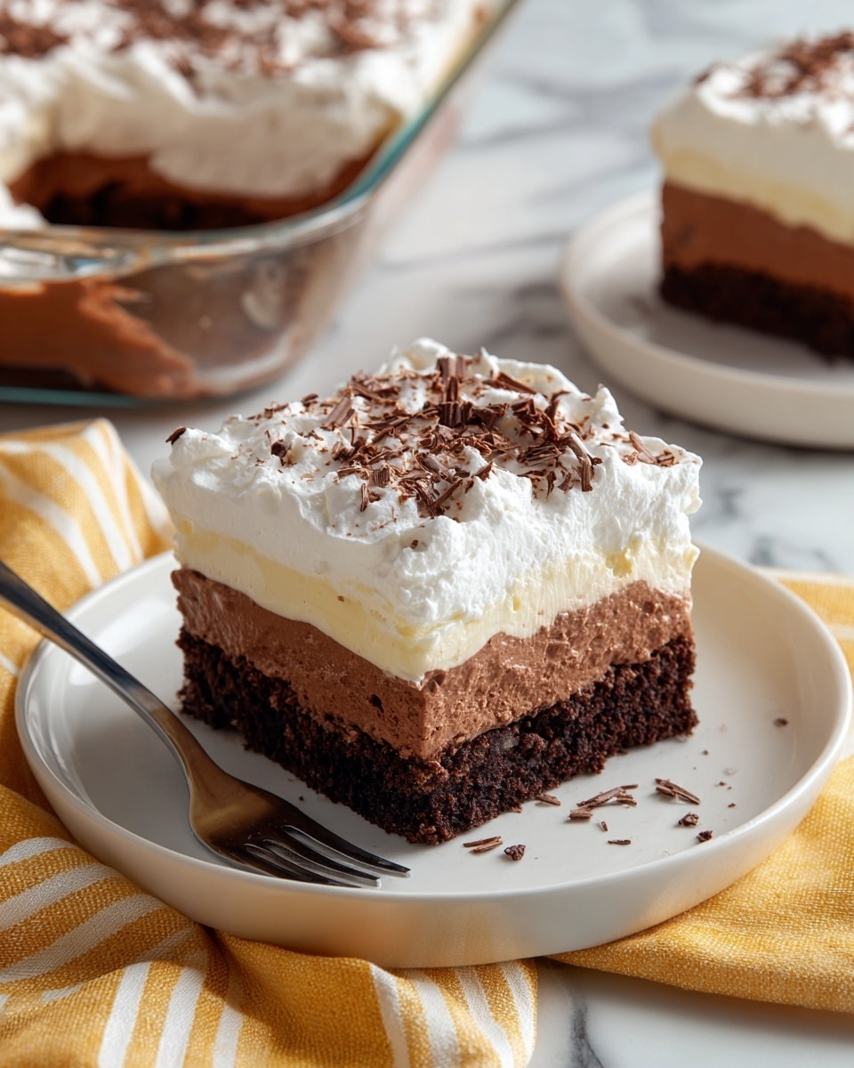 A square piece of layered dessert on a white plate shows three clear layers: at the bottom is a dark, crumbly chocolate crust, topped by a thick, creamy milk chocolate layer with a smooth texture, and finished with a thick, fluffy white whipped cream layer. The whipped cream is sprinkled lightly with fine chocolate shavings on top. The plate is next to a shiny silver fork, and in the background, the rest of the dessert sits in a glass baking dish with a missing section where the piece was cut, all set on a white marbled surface with a yellow and white striped cloth draped casually around it. photo taken with an iphone --ar 4:5 --v 7