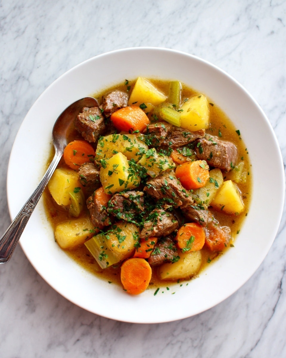 A white plate filled with a stew that has three main layers: diced brown beef chunks mixed with small yellow potato cubes form the base, bright orange carrot pieces shaped like thick coins and green celery slices add color and texture on top. The dish is covered with a light brown broth that makes the stew look juicy and soft, sprinkled with finely chopped green herbs for freshness. A silver spoon rests inside the plate on the left side. The plate sits on a white marbled surface. photo taken with an iphone --ar 4:5 --v 7