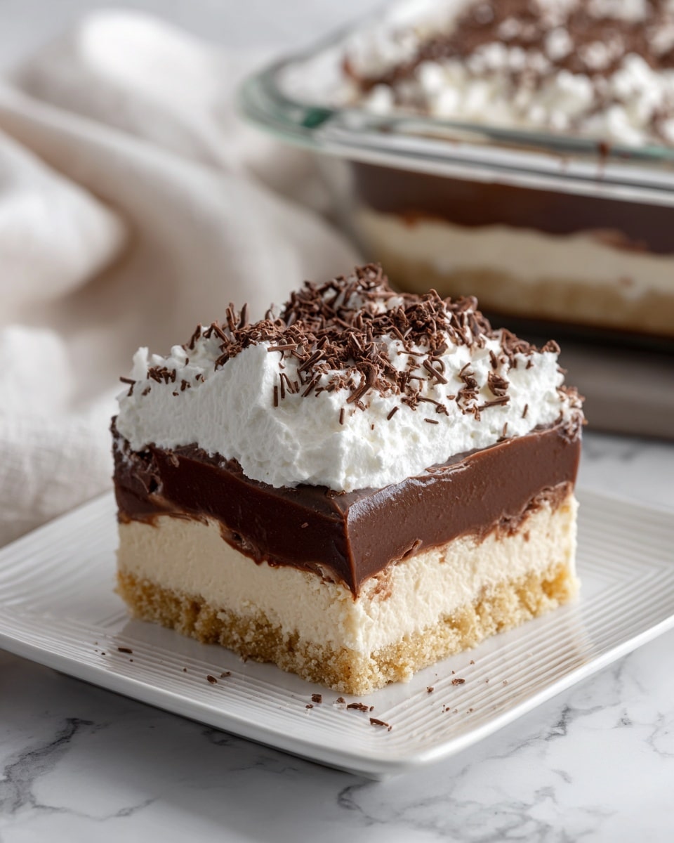 A square piece of layered dessert sits on a white square plate with a subtle linear pattern. The bottom layer is light brown and crumbly, resembling a cookie or graham cracker crust. Above it is a thick, creamy beige layer, smooth in texture. The third layer is a rich, dark chocolate pudding, glossy and dense. On top, a thick, fluffy white whipped cream layer is evenly spread, sprinkled with fine dark chocolate shavings. In the background, a clear glass baking dish holds more of the dessert, sitting on a white marbled surface with a soft white cloth nearby. Photo taken with an iphone --ar 4:5 --v 7