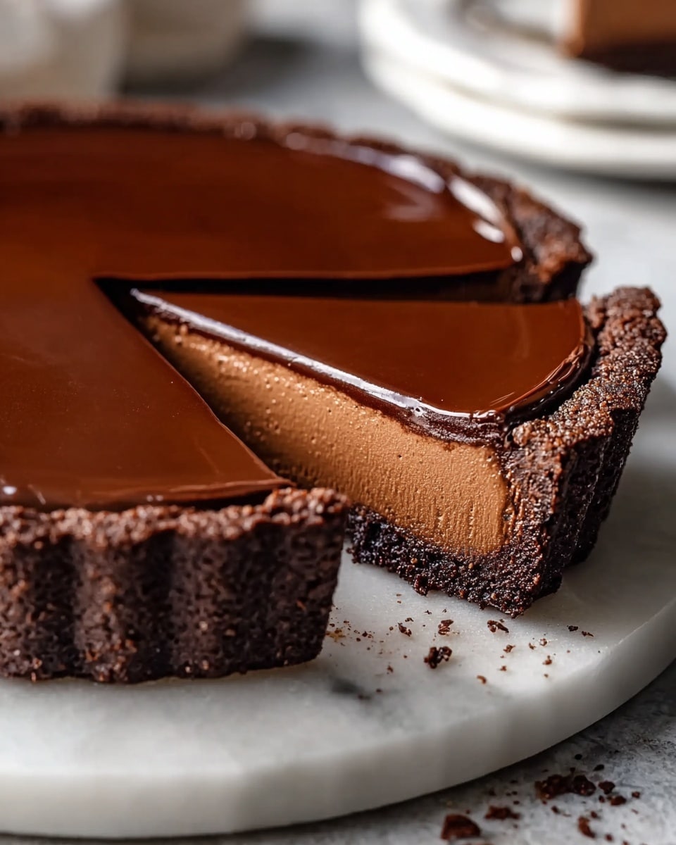 The image shows a rich chocolate tart with three visible layers, placed on a white marbled plate. The bottom layer is a dark brown crumbly chocolate crust that forms the base and sides of the tart. Above this crust is a thick, smooth, and creamy milk chocolate filling, light brown in color with a mousse-like texture. The top layer is a glossy, dark chocolate ganache that is thin and shiny, covering the entire surface of the tart. A wedge-shaped slice is cut out from the tart, revealing the clean layers inside. The background is softly blurred with a white marbled texture under the plate. Photo taken with an iphone --ar 4:5 --v 7