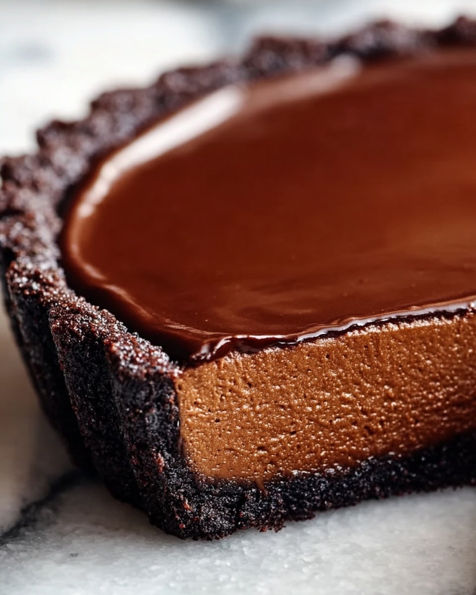 A close-up view of a chocolate tart with three clear layers, sitting on a white marbled surface. The bottom layer is a dark, crumbly chocolate crust that forms the base and sides of the tart. Above that is a thick, smooth chocolate filling with a rich, slightly porous texture and a medium brown color. The top layer is a glossy, dark chocolate ganache that sharply contrasts with the matte filling beneath, spreading thinly to the edges with a slightly uneven surface. The tart edge has a rough, bumpy texture where the crust meets the filling and ganache, emphasizing its handmade look. Photo taken with an iphone --ar 4:5 --v 7