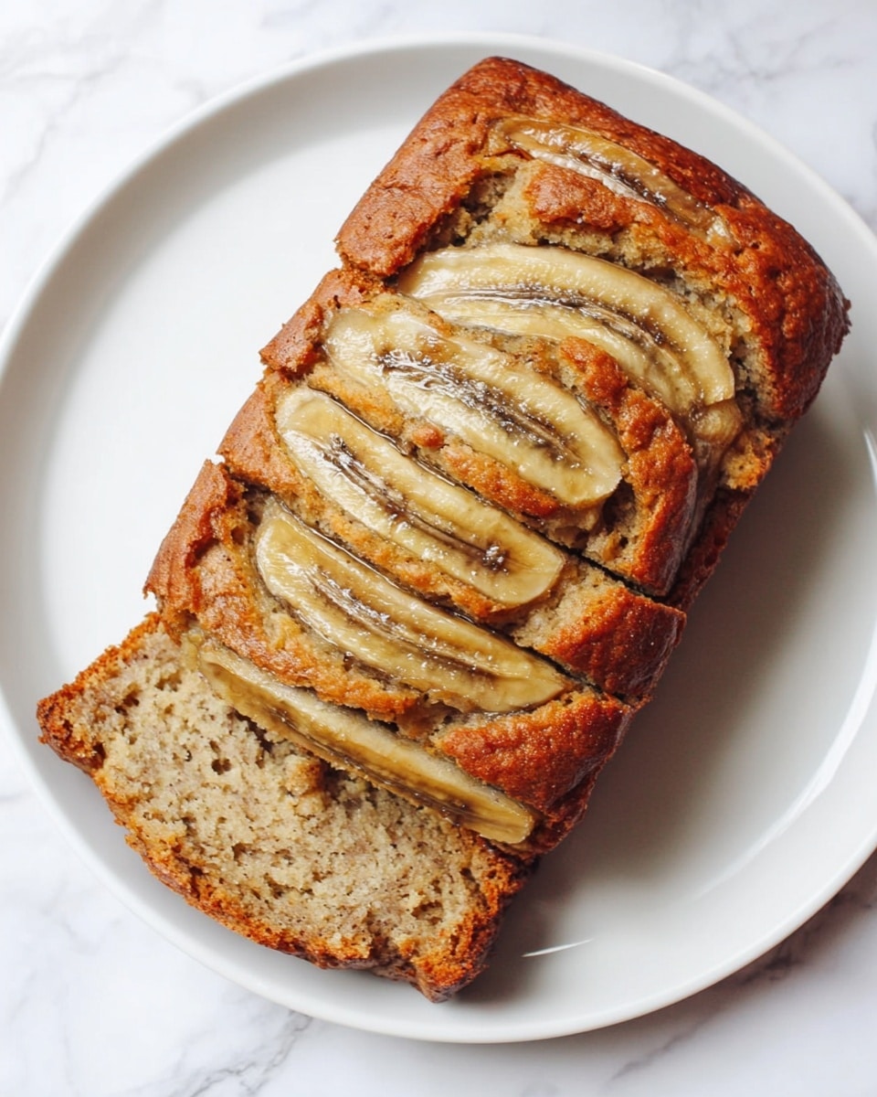 A loaf of banana bread sliced into five pieces, showcasing a moist and dense texture with a light brown color speckled with darker brown bits inside. The top has a golden crust with visible chunks of banana arranged in horizontal stripes, slightly caramelized and soft looking. The bread rests on a smooth white plate placed on a white marbled textured surface. Photo taken with an iphone --ar 4:5 --v 7