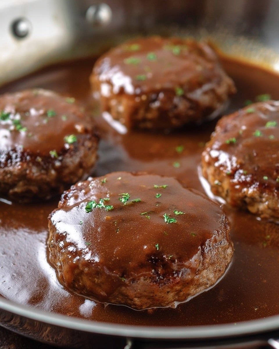 The image shows four thick, round meat patties cooking in a shiny silver skillet, each covered with a glossy, rich brown gravy sauce sprinkled with small green herb pieces. The patties have a slightly rough texture with some small cracks on the surface, and the sauce pools smoothly around them, reflecting the light and showing some ripples. The close-up shot highlights the juicy and tender look of the meat and the thick consistency of the gravy. photo taken with an iphone --ar 4:5 --v 7